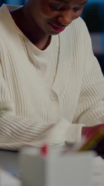 İş dünyasından Afrikalı bir kadının portresi bilgisayardan başını kaldırdıktan sonra kameraya gülümsüyor. Gece geç saatlerde yeni başlayanlar şirketinde oturuyor. Projenin bitiş tarihine saygı göstererek fazla mesai yapan odaklı çalışan