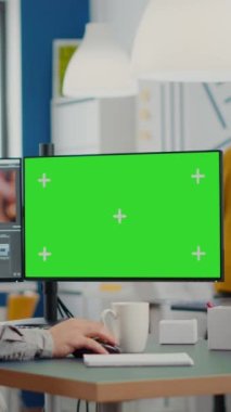 Krom tuşlu bilgisayar kullanan bir kameraman, izole görüntü düzenleme videosu ve ses görüntülerini oluşturur. Ekip arka planda çalışırken, adam editörü yeşil ekran ile bilgisayar üzerindeki film montajını işliyor