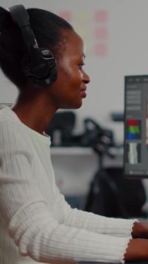 Siyahi kadın video editörü modern yaratıcı ajans ofisinde oturan yeni proje filmi montajı yapıyor. Post prodüksiyon yazılımı ile dijital multimedya şirketi işleme filminde içerik oluşturucu