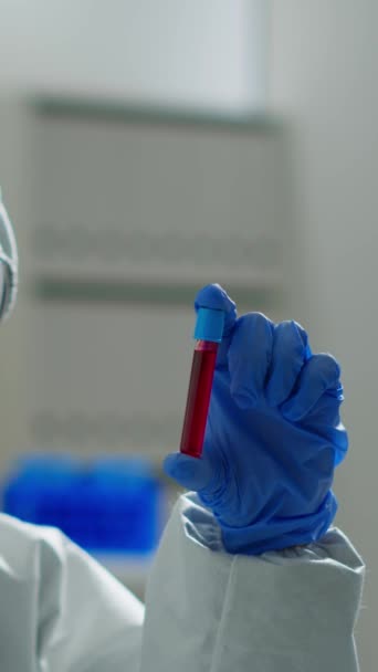 垂直ビデオ 医学研究所で働く化学反応を分析する血液サンプルを保持している全体の生化学者 高度な技術を用いてワクチンの進化を調べる科学者 — ストック動画