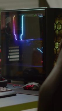 Dikey video: RGB güçlü kişisel bilgisayar ve oyun stüdyosunda hiç kimse olmadan birinci şahıs nişancı oyunu ekranda. Modern tasarıma sahip boş rahat oda sıcak ve neon ışıkla aydınlatılıyor..