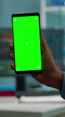 Dikey video: Krom anahtar, laboratuvar dolabındaki bilim kadını tarafından kullanılan akıllı telefondan izole edilmiş görüntü ve beyaz önlüklü meslektaşlar kan örneği getiriyorlar. Bilim adamı model yeşili olan cep telefonu kullanıyor