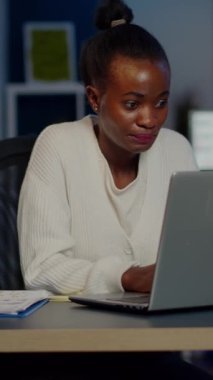 İş yerinde baş ağrısı çeken stresli Afrikalı iş kadını gece geç saatlere kadar çalışıyor. Yorgun, gergin, migrenle baş eden, duygusal stres konsepti laptopta çalışırken acıyı hisseden bir işçi.