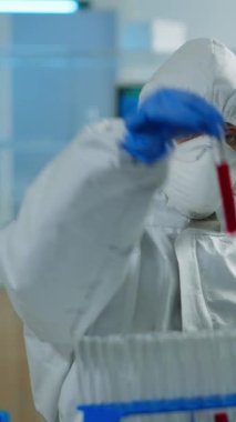 Dikey video: Pen giysili nörolog aşı geliştirme bölümünde çalışıyor ve bilgisayar üzerinde kan örneklerini analiz ediyor. Ekip araştırma için yüksek teknoloji kullanarak virüs evrimini inceliyor.