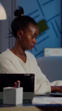Bilgisayarda ve tablette aynı anda çalışan çok görevli siyahi iş kadını. Başlangıç ofisinde fazla mesai yapıyor. Afrikalı çalışan, mali istatistikleri incelemekle meşgul. Aşırı çalışma, arama..