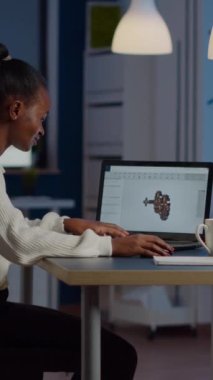 Gece geç saatlere kadar çalışan Afrikalı mühendis laptop 'daki endüstriyel viteslerin 3D modeli üzerinde çalışıyor. Freelancer aygıt ekranında küçük yazılımları gösteren bilgisayar üzerinde prototip fikri üzerinde çalışıyor