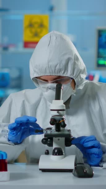 Vertical Video Scientist Ppe Suit Making Adjustments Looking Laboratory Microscope — Stock Video