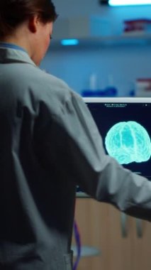 Dikey video: Araştırmacı arka plandaki hastayla yan etkiler, beyin fonksiyonları, sinir sistemi ve tomografi taramalarını tartışırken beyin taramasını inceliyor
