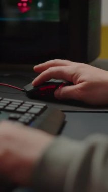 Dikey video: Çevrimiçi nişancı oyunu oynarken RGB klavye tuşlarına basan adamın el kamerasını kapat. Sanal nişancı oyunu siber uzayda sahneleniyor, esports oyun esportları çevrimiçi