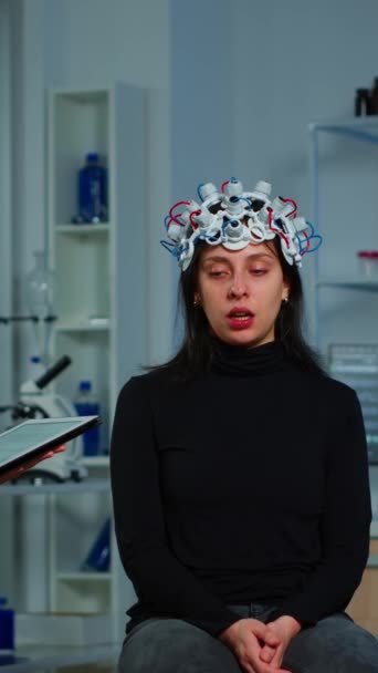 垂直ビデオ 研究者神経科医は 患者にタブレットでメモを取る症状を尋ねる ハイテクの目のヘッドセットを調整 脳機能を解析する脳波ヘッドセットを制御する医師研究者 — ストック動画