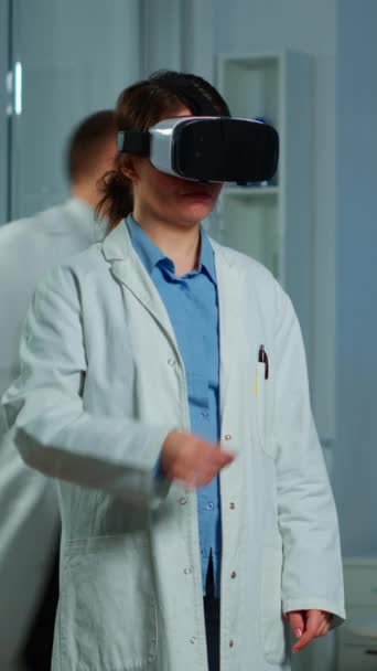 垂直ビデオ 患者の脳スキャンを分析する研究室で医療イノベーションを使用して仮想現実メガネを着用する専門研究者 機器を扱う神経内科医のチーム ハイテク — ストック動画