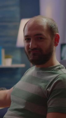 Dikey video: Astar adam kameraya bakıp gülümserken video oyunlarını canlı yayında sohbet ederek yayınlıyor. Oyun alanında RGB 'de bilgisayar oyunu oynayan profesyonel siber oyun kurucu.