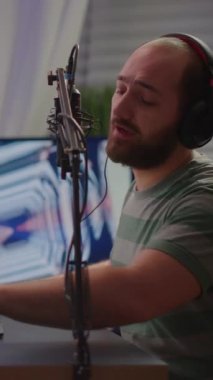 Dikey video: Kulaklıklı profesyonel dijital oyuncu modern grafikli video oyunu oynatıyor. Çevrimiçi oyun oynayan karıştırıcının sesini kontrol eden profesyonel oyuncu