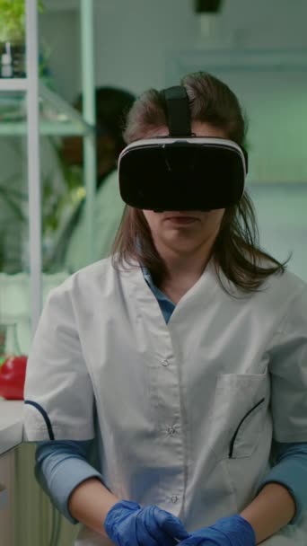 垂直ビデオ 生物学的実験のための新しいバイオテクノロジーを開発する仮想現実ヘッドセットを身に着けている科学者女性研究者 Dna検査を解析する微生物学研究室で働く医療チーム — ストック動画