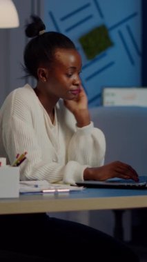Çok çalışan Afrikalı yönetici kadın, iş yerinde dizüstü bilgisayarda fazla mesai yaparken kafa masajı yapıyor. Yorgun iş kadını, migrenle başa çıkma tarihine saygı duyuyor.