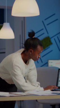 Finansal raporlar üzerinde çalışan siyah muhasebeci istatistikleri kontrol ediyor, dizüstü bilgisayarlara bakıyor, gece geç saatlerde yeni açılan ofiste son teslim tarihine uymak için fazla mesai yapan rakamlara işaret ediyor.