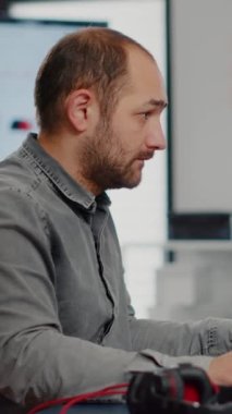 Kameraya bakan erkek video editörü, iki ekranlı görüntü ve sesle çalışıyor. Başlangıçta film montajı için uygulama yazılımı kullanarak kameraya gülümseyen film kurgusu.