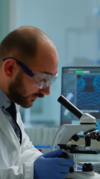 Pionowe Wideo Mężczyzna Naukowiec Patrząc Pod Mikroskopem Laboratorium Rozwoju Medycznego — Wideo stockowe