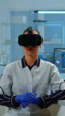 Dikey video: Laboratuvar doktoru tıbbi araştırma laboratuvarında video gözlük kullanarak sanal gerçekliği tecrübe ediyor. Tıbbi yenilik teçhizatı kullanan terapist gözlükler, gelecek, tıp, hekim