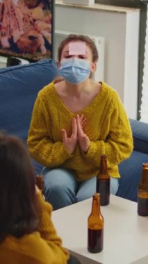 Dikey video: Alnında yapışkan notlar olan komik arkadaşlar, yeni normal parti sırasında yüz maskesi takarak isim oyunundan keyif alıyorlar ve sosyal mesafeyi kovid19 'un yayılmasını engelliyorlar. İnsanlar eğleniyor