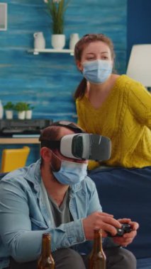 Dikey video: Heyecanlı adam, küresel pandemikte koronavirüsün yayılmasını önlemek için vr kulaklık takarak oyun oynayan arkadaşlarıyla vakit geçiriyor. Değişik insanlar yeni gelenlerle eğleniyor.