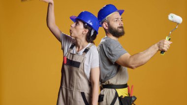 Boya fırçası ve silindirle duvarları boyama becerisine sahip bir inşaat ekibi, fırça ve renkleri yenilemek için kullanıyor. İnşaatçılar stüdyoda yeniden geliştirme ve inşa üzerinde çalışıyorlar..