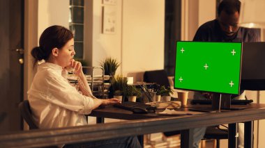 Bilgisayarda yeşil ekran görüntüsüne bakan genç bir yetişkin, bilgisayarın arka planında izole edilmiş bir kopyalama alanı ile çalışıyor. Küçük işletme ofisinde boş krom anahtar şablonu kullanılıyor. Üçayak atışı.