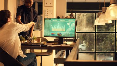 Sabit telefon ve finansal satış verileriyle çalışan çalışanlar şirket hisseleriyle araştırma sunumu planlıyorlar. Bilgisayardaki yönetici yatırım raporu analiz ediliyor.