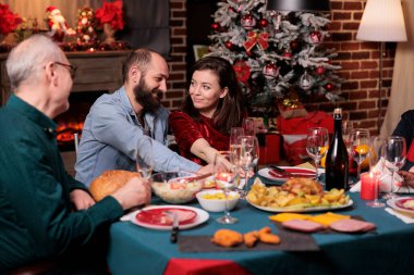 Romantik çift Noel 'i ailesiyle kutluyor, mutlu sevgili ve sevgililer şenlikli yemek masasında konuşuyorlar. Xmas kutlaması, karı koca aileleriyle geleneksel yemek yiyor.