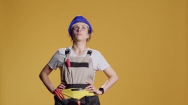Kadın inşaat işçisi portresi. Başı dönüyor ve çizgi film yıldızlarını görüyor. Sersemlemiş ve titrek davranıyor. Kafası karışık, titrek, neredeyse bayılacak gibi, stüdyoda çılgın melodiler çalıyor..