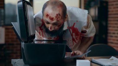 Giysileri kanlı aptal zombi ofiste kendi suratının fotokopisini çekiyor. Korkunç kıyamet günü kanlı yaraları olan ölü bir ceset şirket çalışma alanında fotokopi makinesine zarar veriyor.