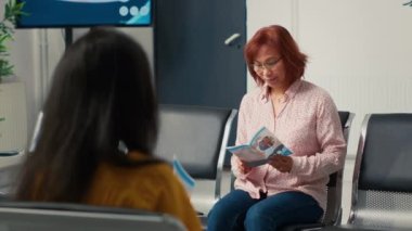 Sağlık merkezindeki bekleme odasında tıbbi sigorta formlarını okuyan, sağlık kontrolüne katılan yaşlı Asyalı kadın portresi. Hasta konsültasyonda doktorla görüşmek için bekliyor..