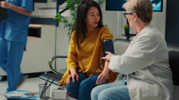 老年医生和亚洲妇女在保健中心用体能计进行高血压测量 用心脏科检测仪检查脉搏压 有医疗预约 — 图库视频影像