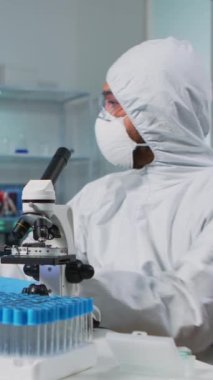 Dikey video: Modern donanımlı laboratuvarda bilgisayar üzerinde DNA örneklerini kontrol eden biyolog doktor. Ekip, yüksek teknoloji ve kimya araçları kullanarak tıbbi laboratuvarda aşı evrimini inceliyor.