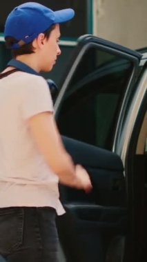 Dikey video: Müşteriye yemek siparişi vermek için araçtan ayrılan servis elemanı. Otomobilden fast food paketi alıp, kurye olarak çalışmak. Üçayak atışı