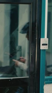 Dikey video: Kadın taşıyıcı ofisin ön kapısındaki kadına fast food paketi sipariş ediyor, ekspres teslimat. Kadın müşteri, kuryeden kese kağıdında restoran yemeği alıyor. El kamerasıyla..