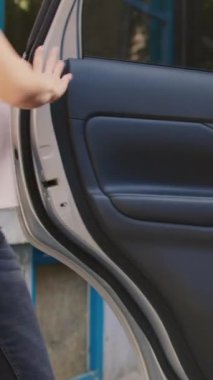 Dikey video: Ofis girişinde fast food siparişi vermek için otomobil kullanan kadın taşıyıcı, restorandan müşteriye yemek veriyor. Arabadan sırt çantası alıp, pizzacı kuryesi olarak çalışmak.
