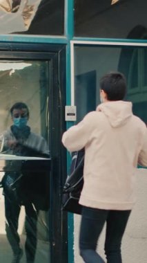 Dikey video: Kadın restoran kuryesi ön kapıdan fast food siparişi veriyor, müşteri öğle yemeğiyle birlikte kese kağıdı alıyor. Paket teslimatı yapan paket servis elemanı. Covid 19 salgını sırasında.