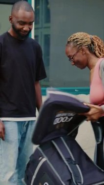 Dikey video: Paket teslimatı yapan kadın, postasındaki kredi kartıyla yemek siparişini ödeyen erkek müşteri. Müşteri, postacıyla bağlantı kurmadan ödeme yapıyor.