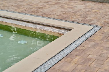 Yürüme yolu ve seramik fayanslar taş ve metal oluklar açık havuz etrafında ızgara ile