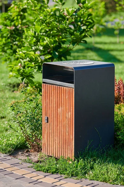 waste basket and cigarette butts in the park landscaping on a green lawn on a sunny day