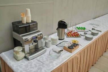 Etkinliğin resepsiyonunda kahve seti, kahve makinesi ve sıcak su ısıtıcıları seminer ziyaretçileri için masada.