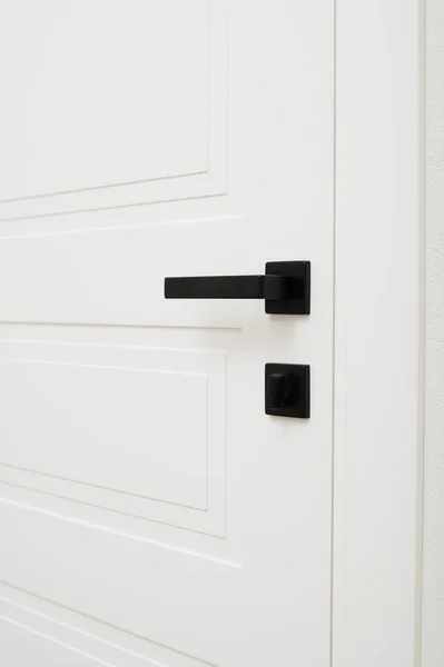 black door handles on a white wooden door, close-up of part of the interior