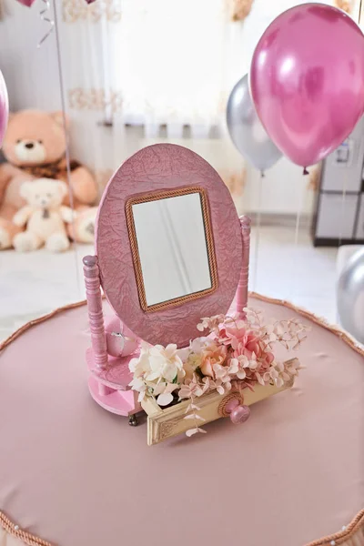 oval mirror in pink with flowers on the table in the children's room