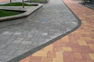 Koltuklu yayalar için iki renkli taş yol. Kentsel bir çevrede kıvrımlı bir yürüyüş yolu.