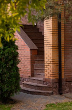 Tuğla binanın ön cephesinde mermer merdiven ve parmaklıklar, binanın bir parçası.