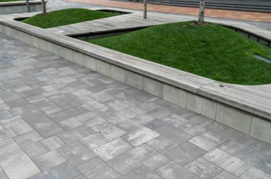 Kavisli bir yürüyüş yolu ve şehir ortamında fayanslardan yapılmış ahşap bir koltuk.