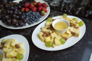 plate with cheese assortment with honey and nuts and fruits on the buffet table for guests at the event