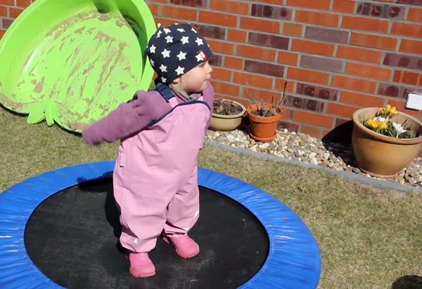 Little girl is trying to jump on the trampoline — Stock Photo, Image