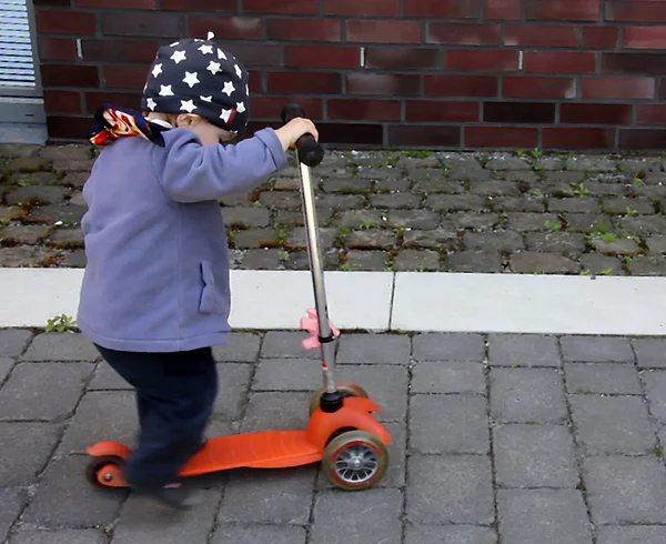 Little girl is trying to ride a large scooter — Stock Photo, Image